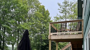 A wooden deck with outdoor furniture, a covered table, and a view of a lake.