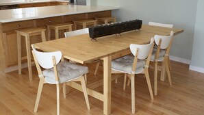 A modern kitchen with a wooden table and chairs, a built-in island, and a long countertop with jars.