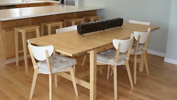 Une cuisine moderne avec une table et des chaises en bois, un îlot central intégré et un long plan de travail agrémenté de bocaux.