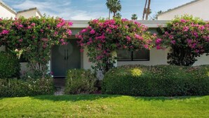 A modern house with a well-maintained garden, including vibrant bougainvillea vines and a neatly trimmed lawn. - Sunrise Villas 3BR condo - Mountain views, relaxing spa & pool and pickleball (Palm Springs)