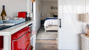 Kompakti hotellihuone, jossa on pieni keittiönurkkaus, sinivalkoinen peitto sängyllä, pieni yöpöytä lampun kanssa ja kyltti, jossa lukee ”BLOCK ISLAND”.