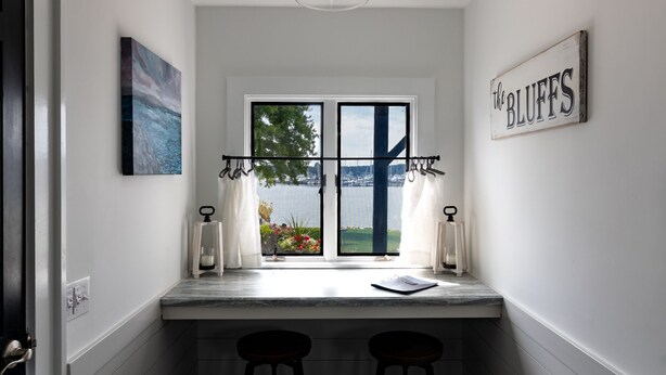 A small kitchen with a view of the water, a bar area with stools, and a sign that reads "the BLUFFS". - Harbor View Landing Mystic, CT - The Bluffs Waterfront House - First Floor ONLY (Mystic)