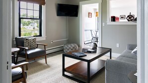 A modern living room with a sofa, armchair, coffee table, and a television mounted on the wall.