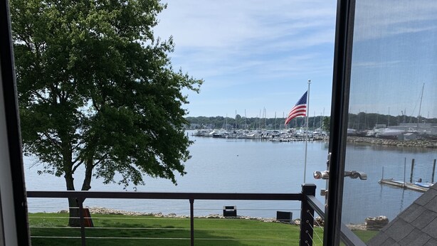 A balcony with a view of a marina, a flag, and a tree.