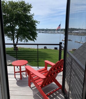 A balcony with a view of a marina, a flag, and a tree.