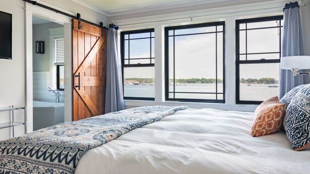 Un dormitorio con una cama grande, una puerta corredera estilo establo y vistas al agua.