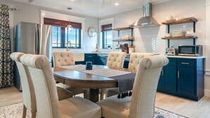 A modern kitchen with a dining area, featuring a round table, tufted chairs, and a built-in oven.