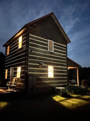 A log cabin with a porch, a chair, and a small window.