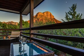 A balcony with a glass-top table, a cushion, and a wine glass.