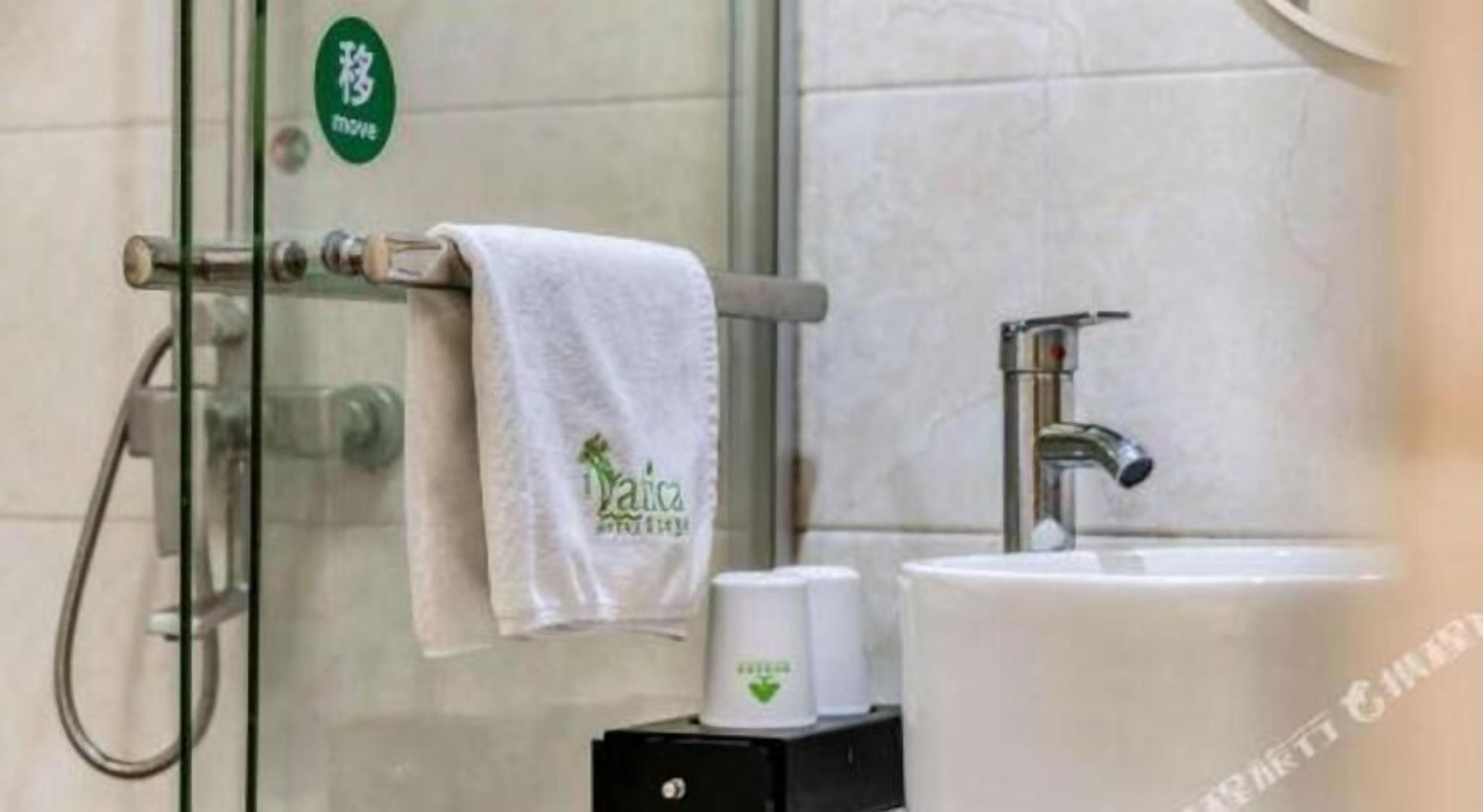 A bathroom with a glass shower enclosure, a white sink, and a towel hanging on a rack.
