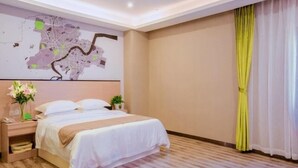 A hotel room with a large bed, a map on the wall, a nightstand with a lamp, and a window with yellow curtains.