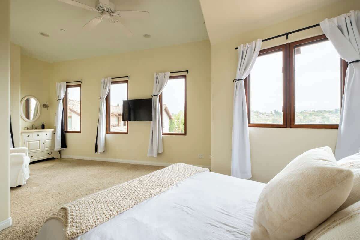 A bedroom with a bed, a dresser, a mirror, and a TV mounted on the wall.