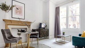 A modern living room with a fireplace, a dining area, and a sofa. - The Chelsea Studio next to Sloane Square (London)