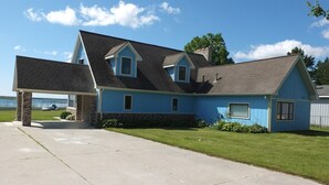 Une maison à deux étages, avec une façade bleue, un porche avant couvert et un garage visible.