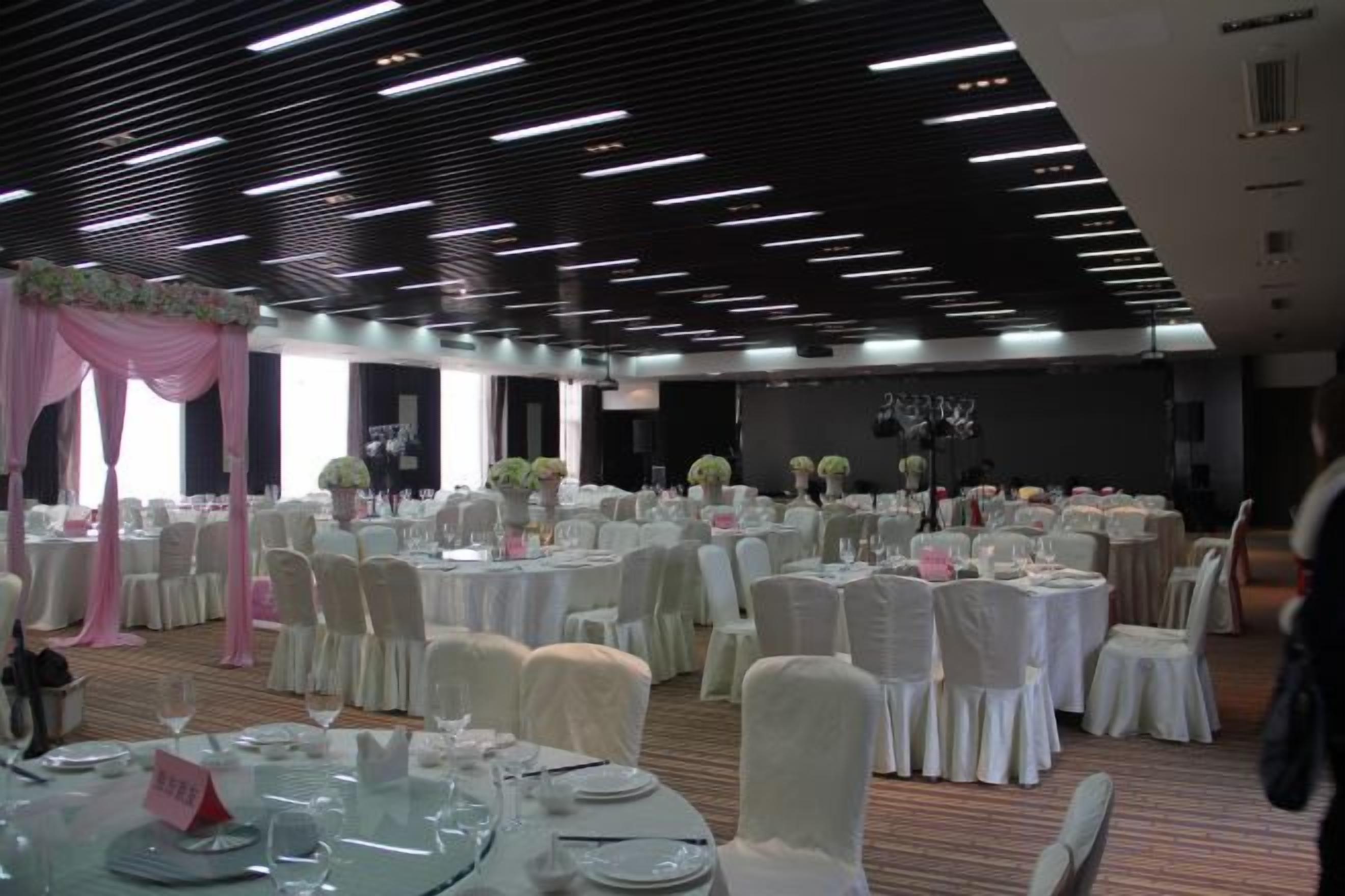 A banquet hall with round tables, chairs, and floral centerpieces.