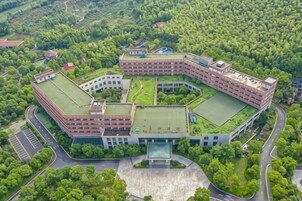Un edificio grande de varios pisos con un patio central rodeado de vegetación.