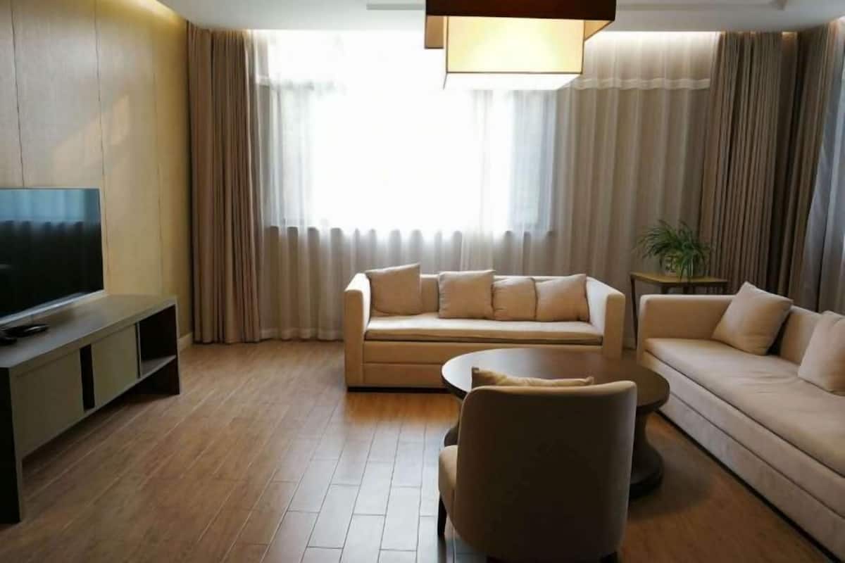 A modern living room with a sofa, armchair, TV, and a small table.