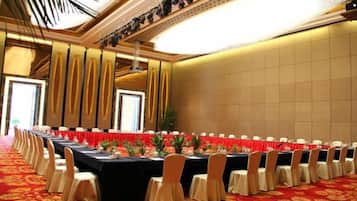 Un salón de conferencias con una larga mesa, sillas y una alfombra roja.