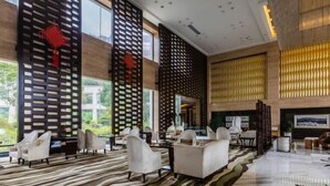 A spacious lobby with a modern design, featuring a large seating area, a fireplace, and large windows offering a view of the outdoors. - Jiangsu Yunhu International Conference Center (Yixing)