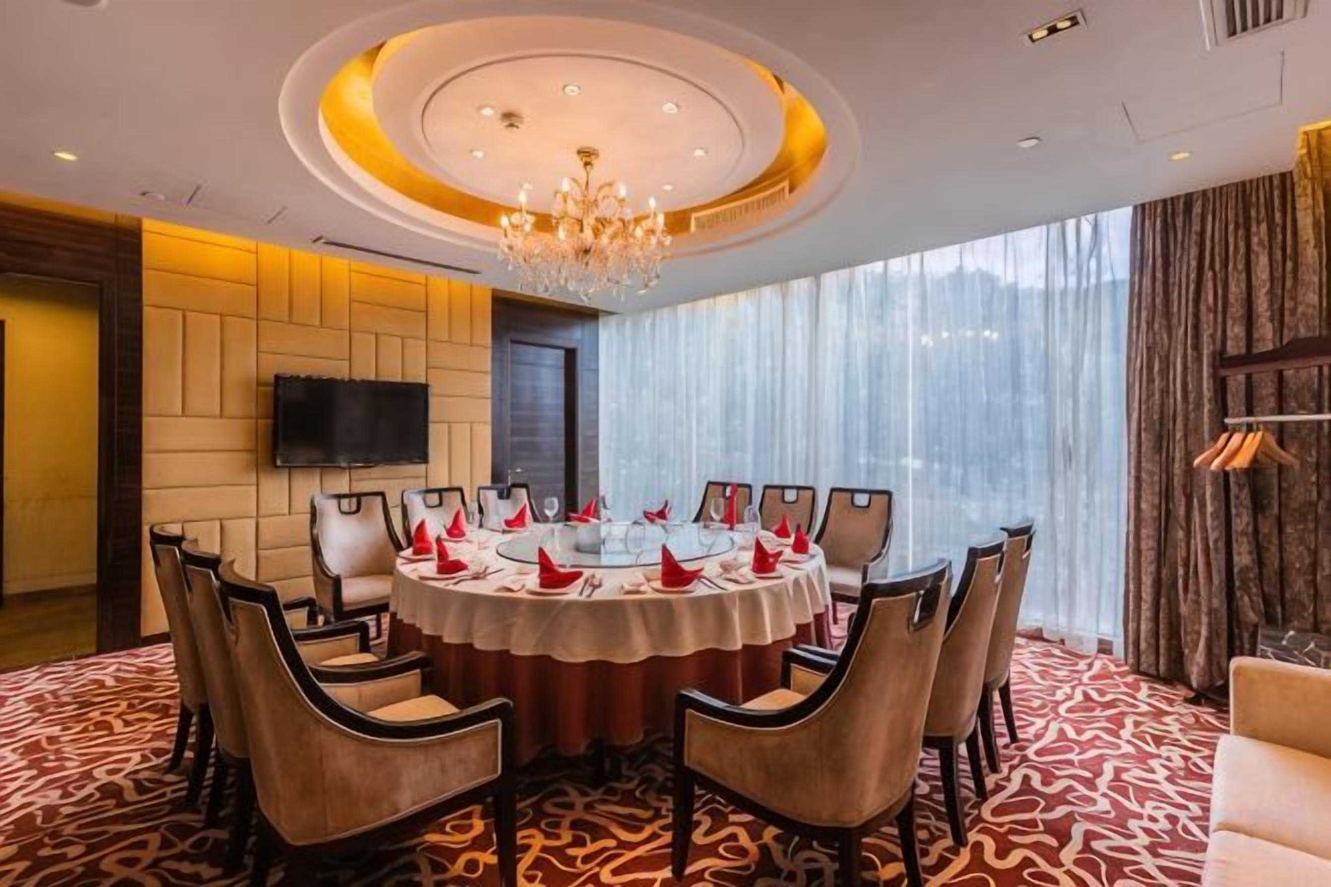 A conference room with a round table, chairs, and a chandelier.