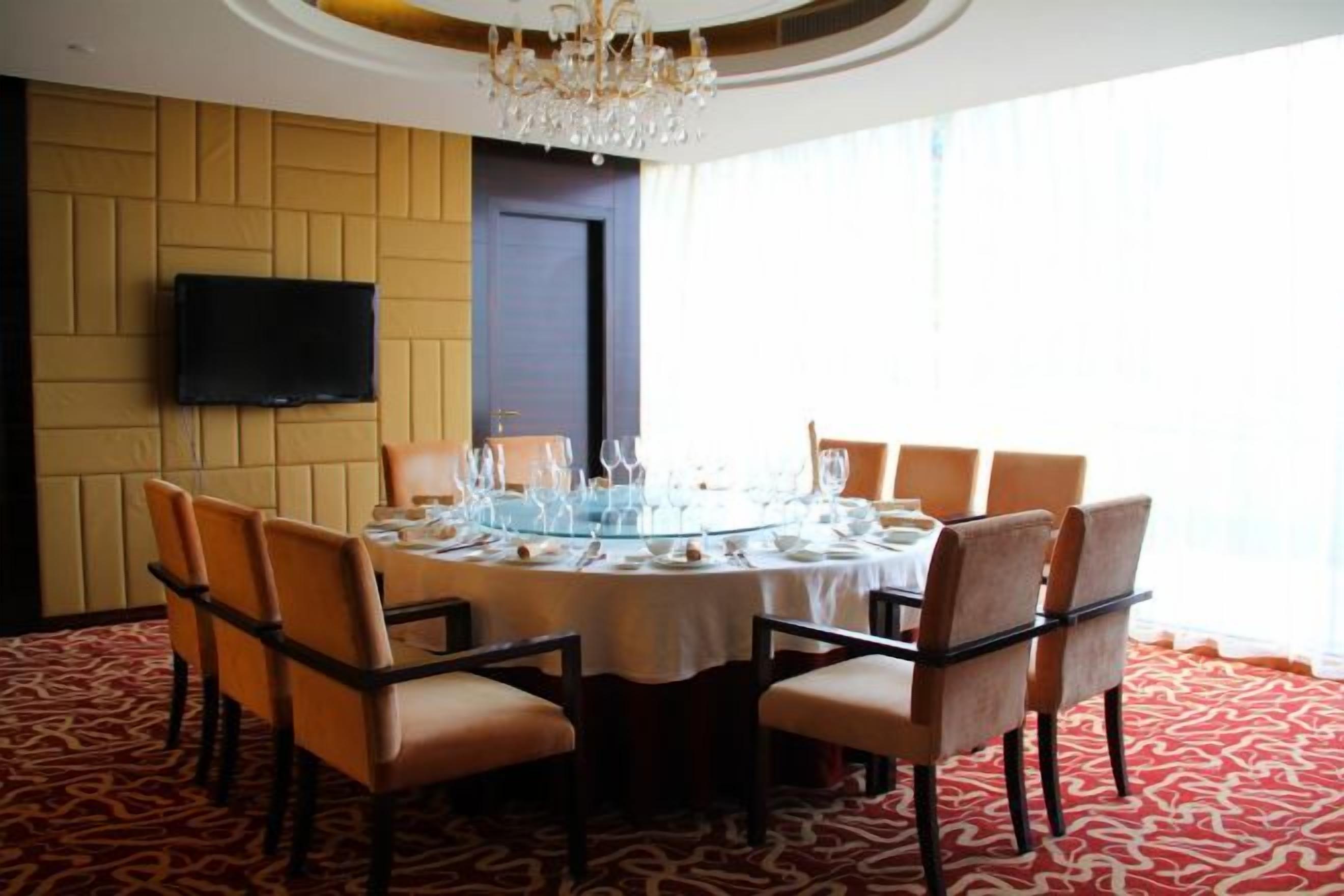 A dining room with a round table, chairs, and a chandelier.