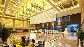 A spacious lobby with a reception desk, seating area, and a large digital screen.