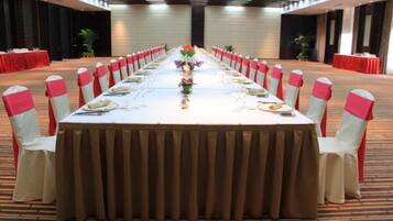 A conference room with a long table set for a meeting, surrounded by chairs with red sashes.
