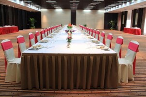 Un salón de conferencias con una larga mesa dispuesta para una reunión, rodeado de sillas con cintas rojas.