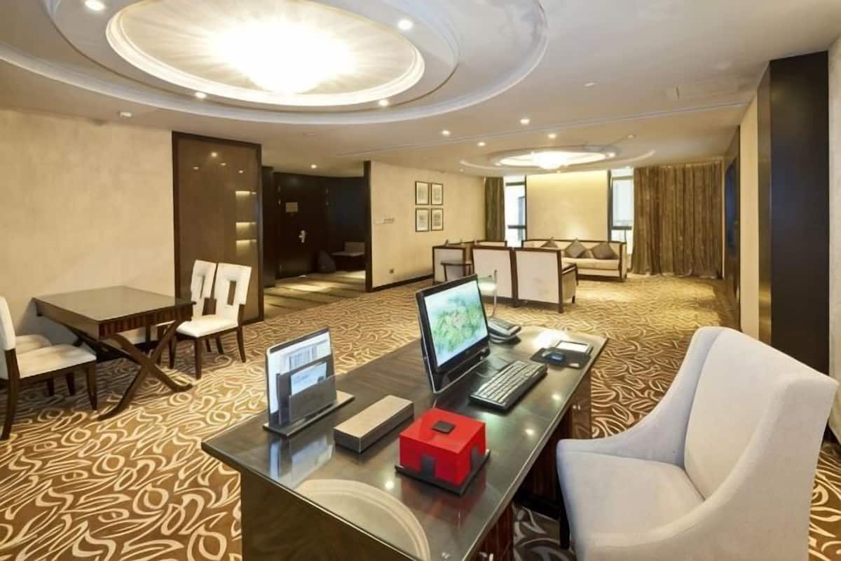 A hotel room with a desk, computer, and seating area.