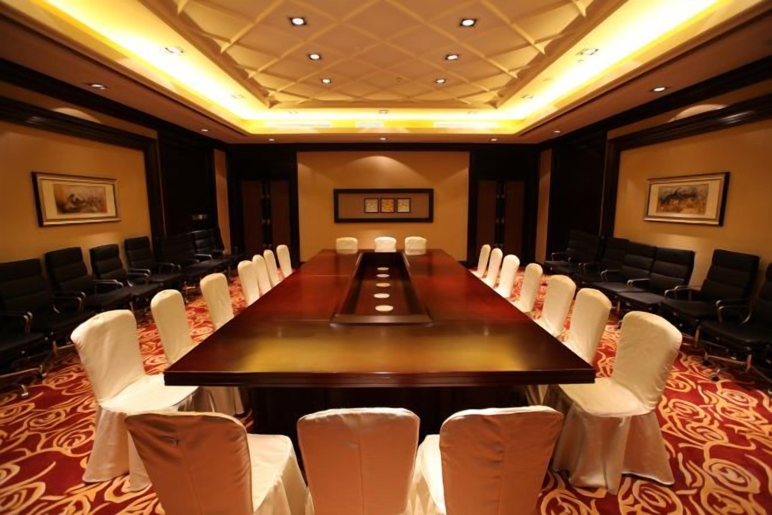 A conference room with a long table, chairs, and a carpeted floor.