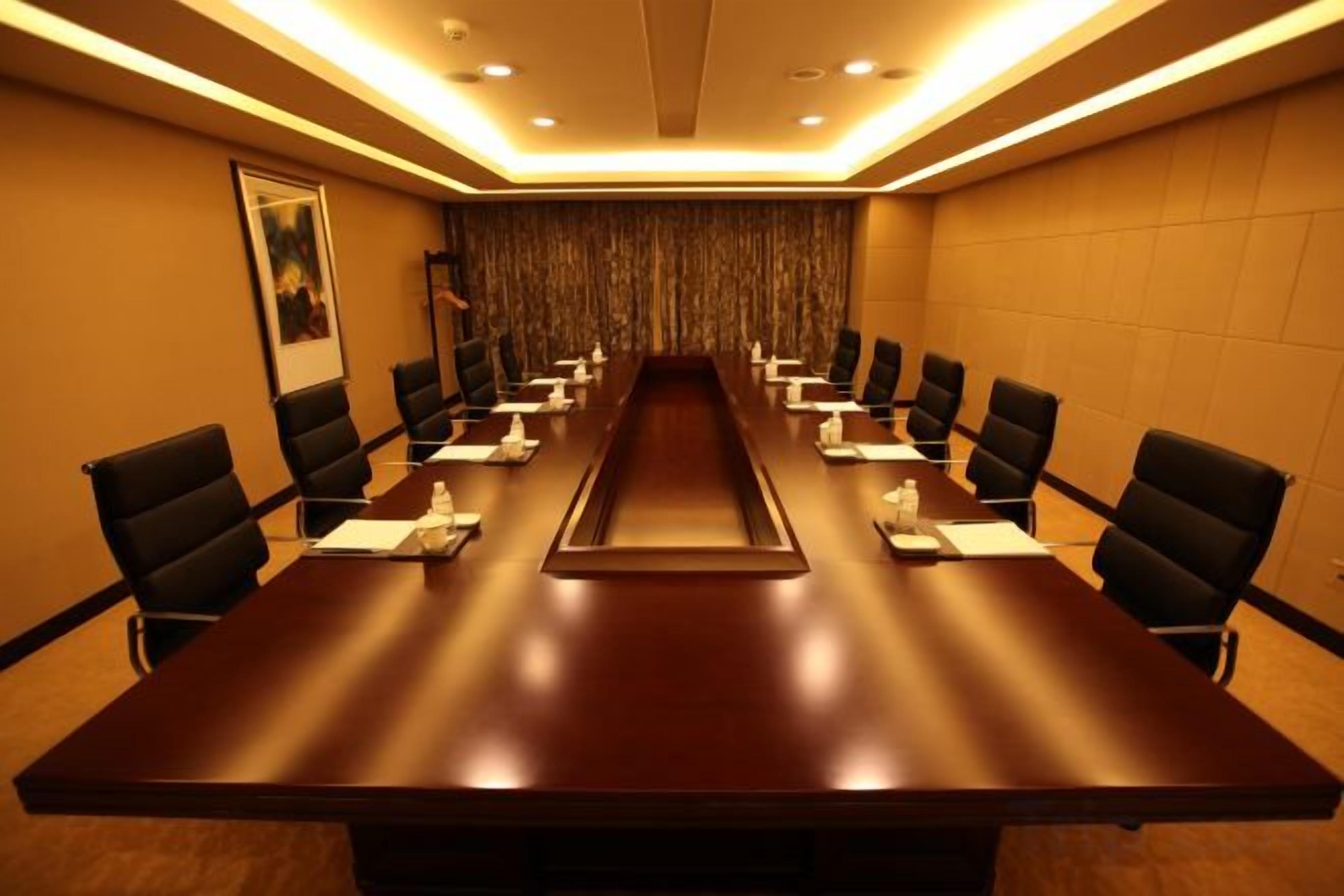 A conference room with a long table, chairs, and a projector screen.