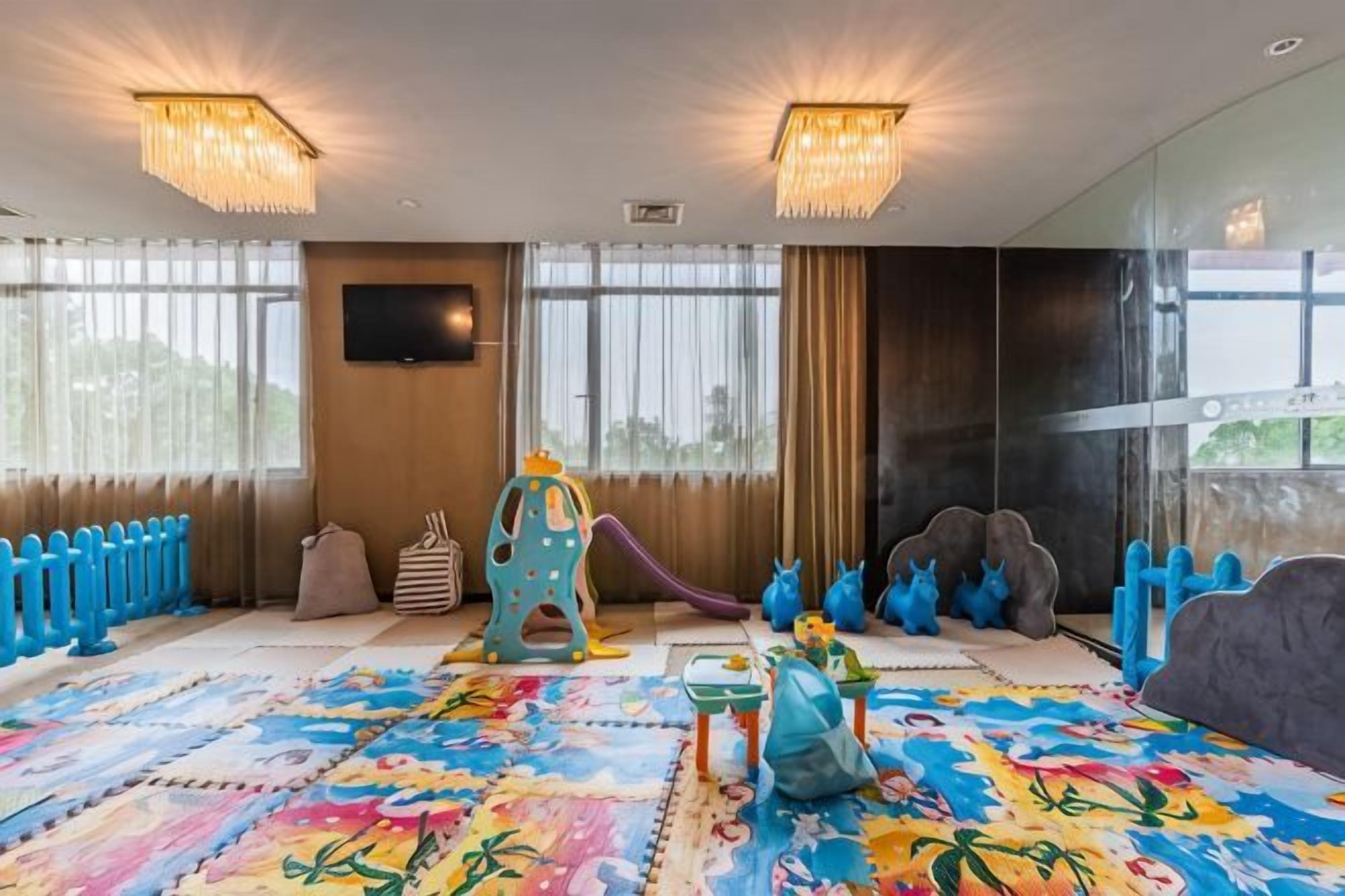 A children's play area with a colorful play mat, a slide, and various play structures.