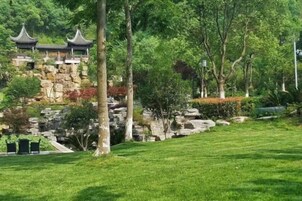 Un edificio tradicional con tejado al estilo pagoda, rodeado de un jardín cuidado con árboles y césped.