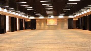 A large, carpeted room with a high ceiling and rectangular lighting fixtures.