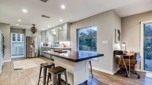 Een moderne keuken met een groot eiland, roestvrijstalen apparatuur en uitzicht op de omgeving.