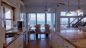 Une cuisine avec vue sur la mer, des chaises en bois et une table à manger.