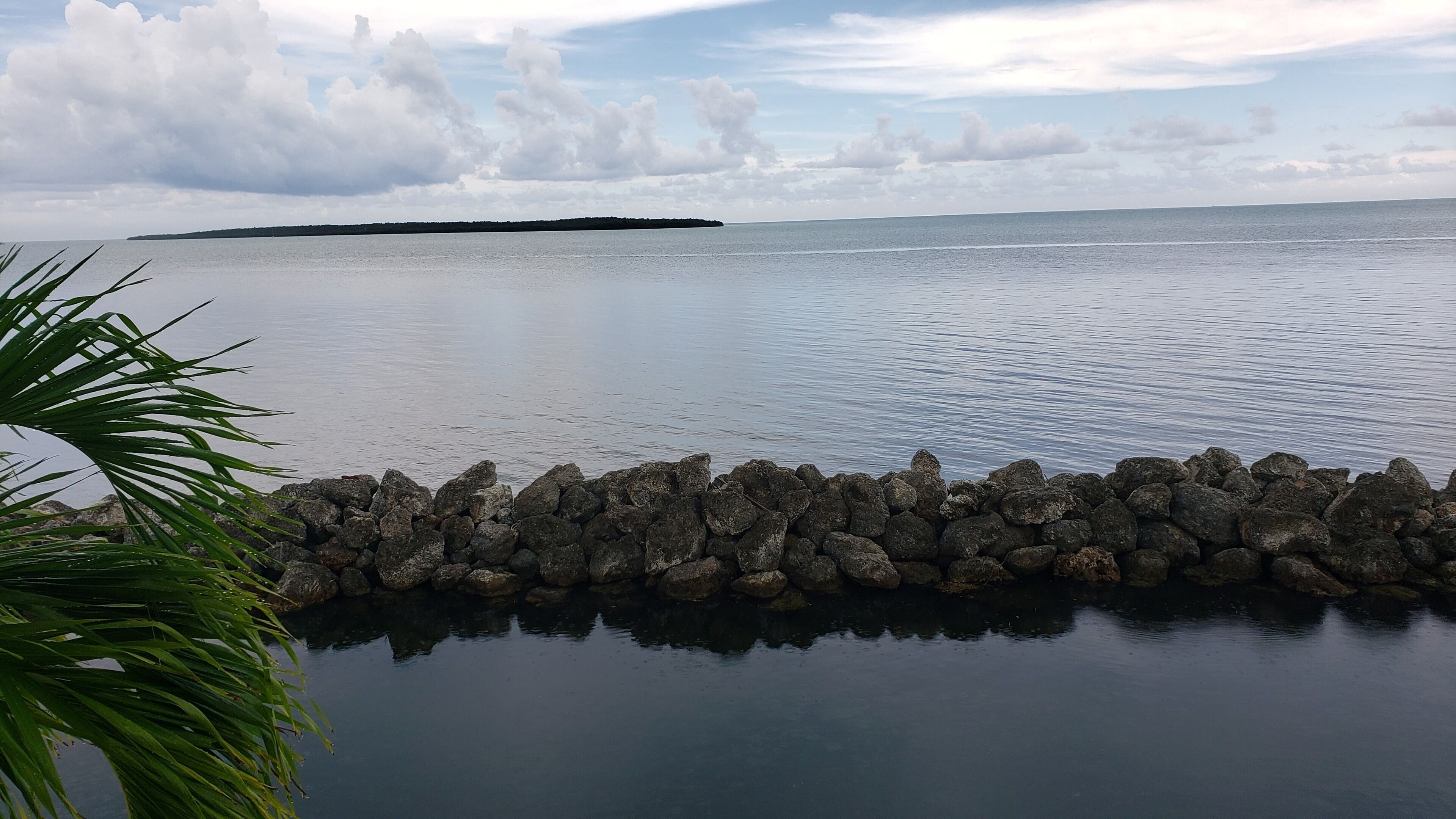Une étendue d’eau calme, bordée d’une côte rocheuse et donnant sur une terre lointaine.