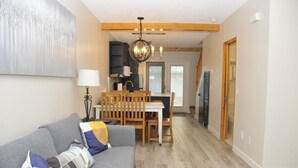 A cozy living room with a gray sofa, wooden dining table, and a chandelier. - ❤ Modern Rustic 2BR 2BTH Mountain Chalet close to Banff (Harvie Heights)