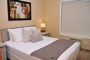 A hotel room with a bed, a nightstand with a lamp, a large window, and a framed abstract painting on the wall. - ❤ Modern Rustic 2BR 2BTH Mountain Chalet close to Banff (Harvie Heights)