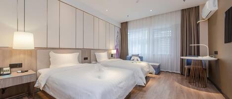 A hotel room with two beds, a desk, a chair, and a small table.