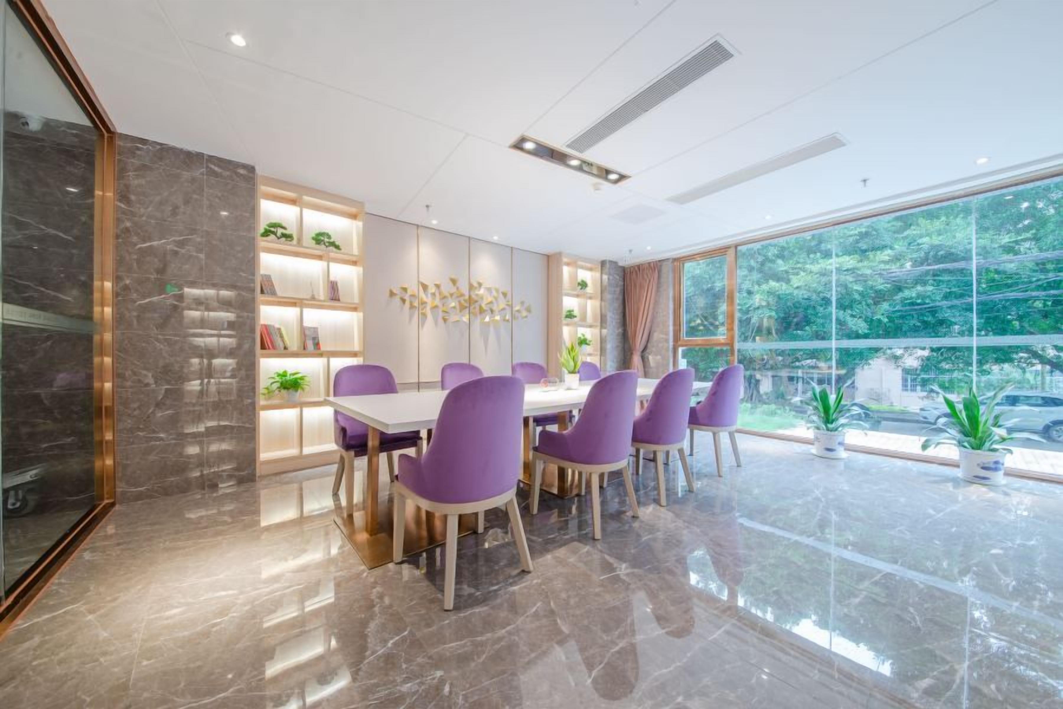A modern dining area with a marble floor, purple chairs, a white table, and a view of greenery through large windows.