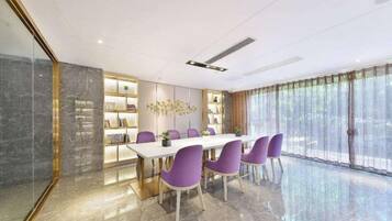 A modern dining area with a marble floor, a white table, and purple chairs.