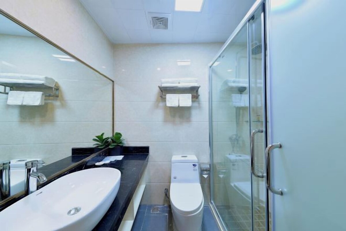 Een moderne badkamer met een groot wastafelmeubel, toilet en een douchecabine van glas.