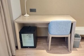 Ein Zimmer mit einem Holztisch, einem Stuhl, einem kleinen schwarzen Gerät, einem Mülleimer und einer Steckdose an der Wand.