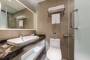 Ein modernes Badezimmer mit Marmorplatte, einem weißen Waschbecken, einer Toilette und einer Duschkabine.