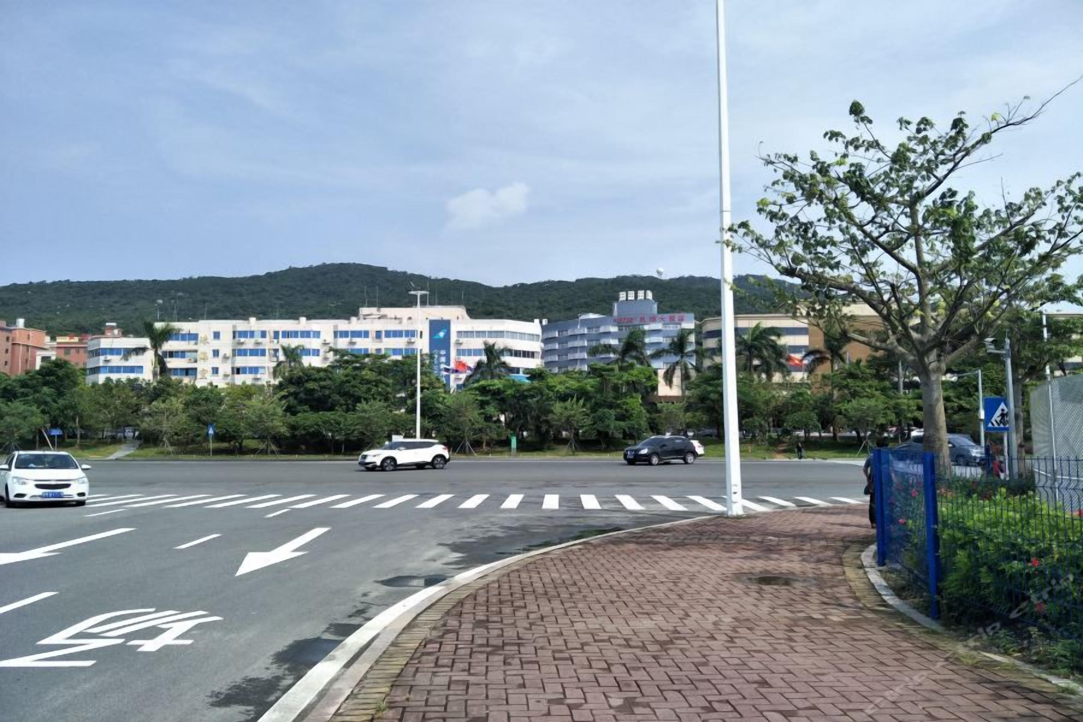 A road intersection with pedestrian crosswalks, vehicles, and a building complex in the background.