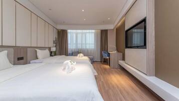 A hotel room with a large bed, a desk, a chair, a TV, and a window.