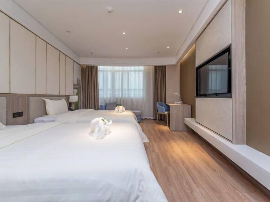 Habitación de hotel con una cama grande, un escritorio, una silla, un televisor y una ventana.