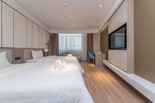 Hotellihuone, jossa on suuri sänky, työpöytä, tuoli, televisio ja ikkuna.