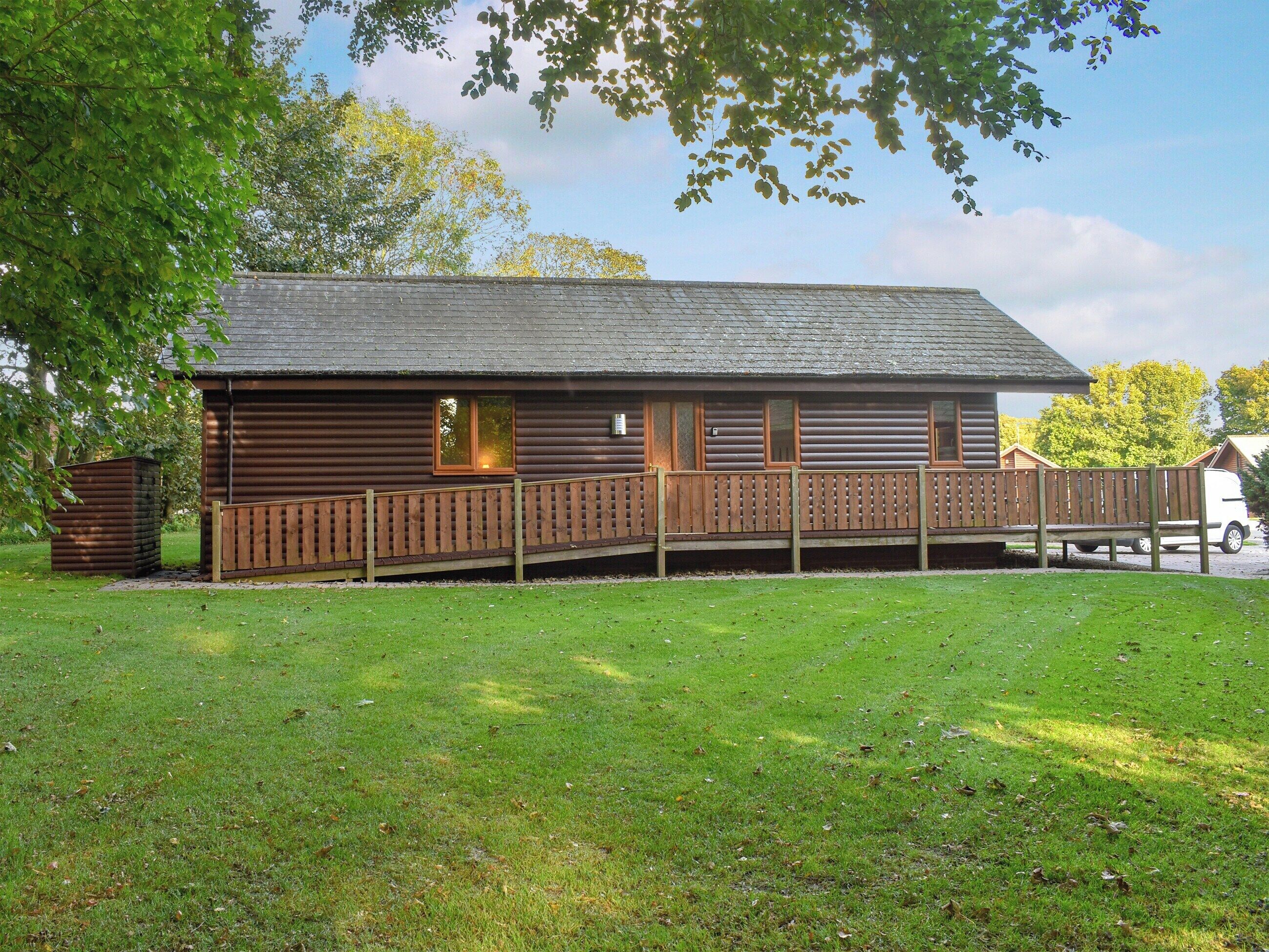 A log cabin with a wooden deck and a fenced area.